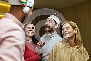 Four diverse friends at New Year's party celebrating and dancing, house guests having fun at Christmas, in New