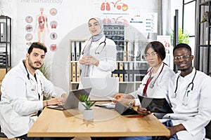 Diverse doctors sitting at conference room with gadgets