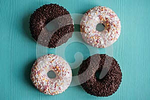 Four donuts, chocolate and white on a turquoise wooden background