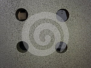 four Drilled holes over a blasted clean grey steel surface photo