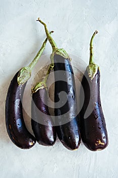 Four eggplants on a white stone background