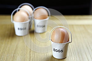 Four eggs in egg cups on a wooden table black background