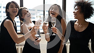 Four elegant multiethnic girls holding champagne glasses celebrating bachelorette party