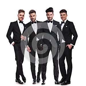 Four elegant young men in tuxedos standing together photo