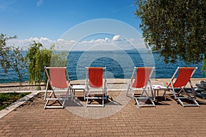 Four Empty Deck Chairs on a beautiful beach on Lake Garda - Veneto Italy