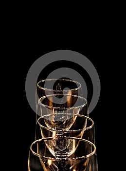 Four empty glass goblets from above on a black background in studio isolated, copy space
