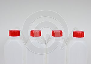 Four empty jerrycans of white plastic with red lids