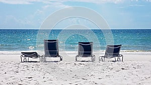 Four empty lounge chairs on an empty beach