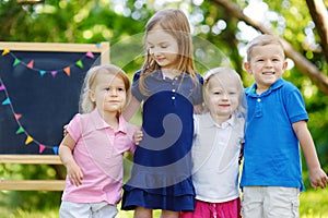 Four excited little kids by a chalkboard