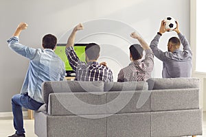 Four excited men friends sitting on sofa and watching emotionally soccer football match