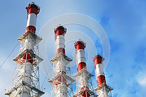 Four factory pipes in bright blue cloudy sky