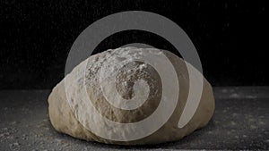 Four falling on fresh raw dough on black background in slow motion. Frame. Cook sifts the flour for the dough