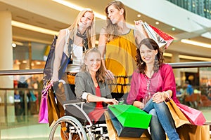 Four female friends shopping in a mall with wheelchair