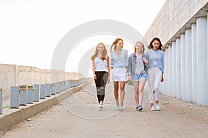 Four female friends walking down at walkway, sunshine background