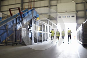 Four figures walking in an industrial interior, soft focus