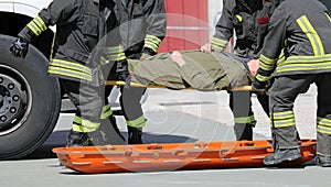 four firemen charge a wounded person on a stretcher