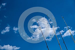 Four fishing rods in row. Blue sky background