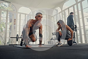 Four fit young adults in sports clothing doing exercises at the gym