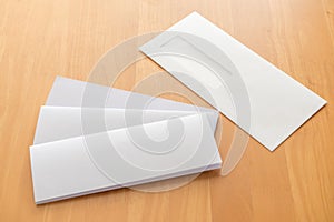 Four fold white template paper with white envelope on wood background