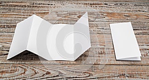 Four - fold white template paper on wood texture .