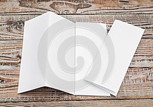 Four - fold white template paper on wood texture .