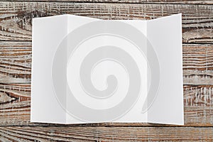 Four - fold white template paper on wood texture .