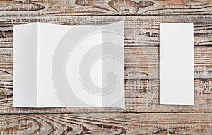 Four - fold white template paper on wood texture .