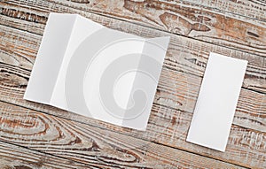 Four - fold white template paper on wood texture .