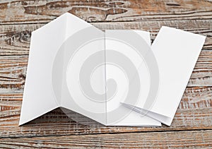 Four - fold white template paper on wood texture .