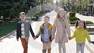 Four friends of children walk in the park, holding hands and laughing. Children walk in the fresh air in the park