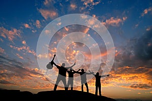 Four friends silhouette on top of a hill with guitar