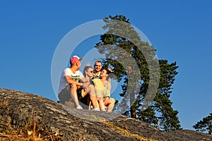 Four friends sitting on edge of mountain at sunset