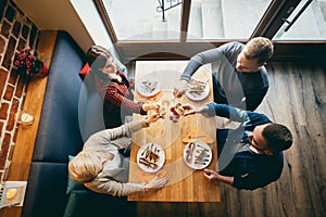 Four friends toasting in a restaurant. Top view.