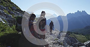 Four friends walking along hiking trail path and relax. Group of friends people summer adventure journey in mountain