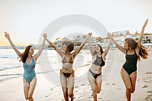 Four girlfriends in swimwear enjoying beach day, female friends having fun during their summer vacation on coastline