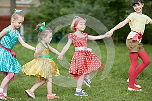 Four girls dance holding hands at grassy