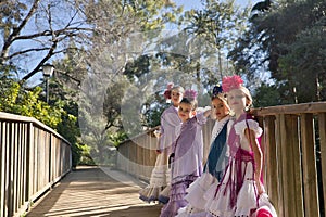 Four girls dancing flamenco, posing looking at the camera, in typical flamenco dress, on a wooden bridge. Concept dance, flamenco