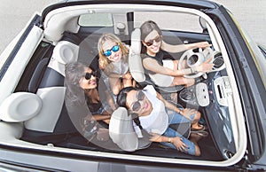 Four girls having fun on a convertible car