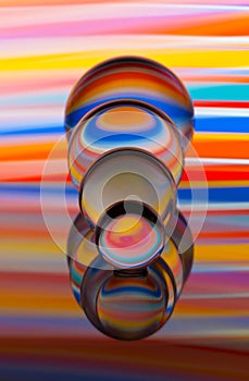 Four glass crystal balls in a row with a rainbow of colorful light painting behind them