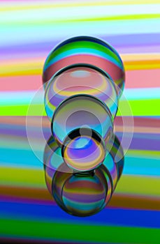 Four glass crystal balls in a row with a rainbow of colorful light painting behind them