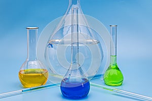 Four glass laboratory flasks with solutions of various colors on a gentle blue medical background. The concept of medical and