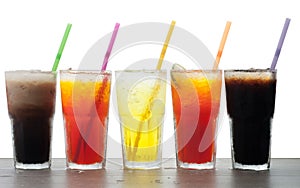 Four glasses of cold, fresh, homemade sodas with ice and drinking straws against a white background. Flavors include orange, rasp photo