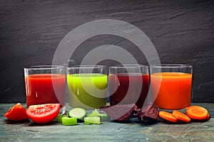 Four glasses of healthy vegetable juice over slate