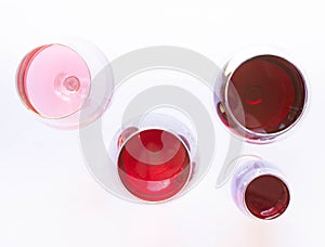 Four glasses of wine: red and pink on white background with sparkling shadows. Top view. Free copy space.