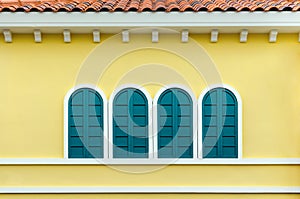 Four green arched windows on yellow wall