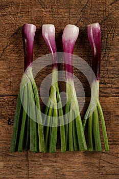 Four green onions on wooden table