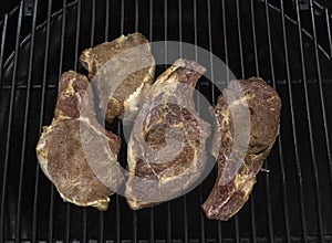 Four half-roasted pork chops on a gas grill