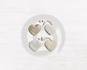 Four handmade hearts from cloth with golden color striped or dots on white wooden background. Valentines Day pattern and