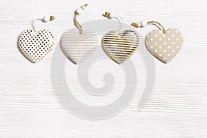 Four handmade hearts from cotton cloth with golden color striped or dots on white wooden background. Valentines Day and