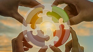 Four hands of businessmen connect colored pieces of the puzzle into a single whole. Business concept idea, partnership